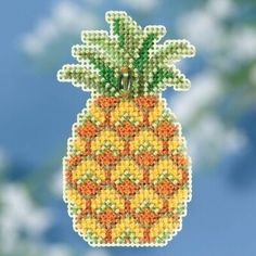 a beaded pineapple ornament hanging on a string with sky in the background