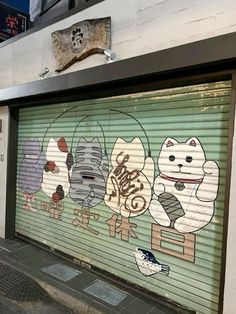 a garage door with cats painted on it's side in front of a building