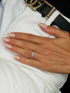 a woman's hand with a diamond ring on her left wrist, wearing a white shirt and black belt