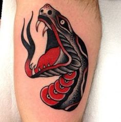 a snake tattoo on the leg of a man with red and black ink, it looks like he's about to strike