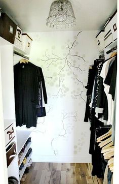 an open closet with clothes on hangers and a chandelier hanging from the ceiling