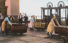 an old photo of people loading items from crates onto carts in front of a building