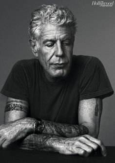 an older man with tattoos sitting at a table