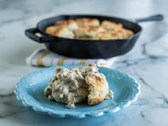 a blue plate topped with food next to a skillet filled with chicken and biscuits