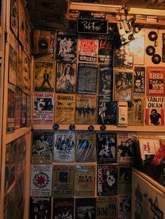 a room filled with lots of different types of posters and records on the wall next to a refrigerator