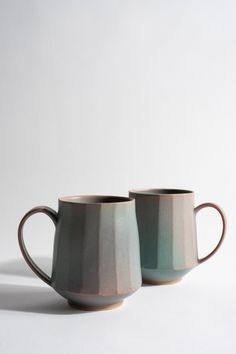 two mugs sitting next to each other on a white surface with no one around them