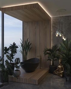 a bath room with a large tub next to plants and a buddha statue in the corner