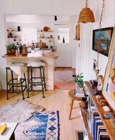 a living room filled with lots of furniture and bookshelves next to a kitchen