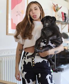 a woman holding a small dog in her arms and making a funny face at the camera