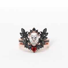 a heart shaped diamond surrounded by black and red stones in a rose gold band ring