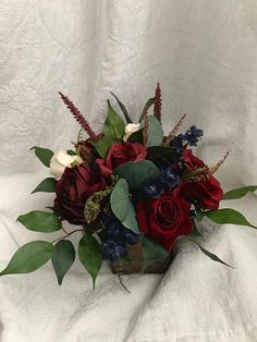 a bouquet of red, white and blue flowers in a wooden box with greenery