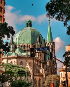 an old building with a green roof and steeples on it's sides in the city