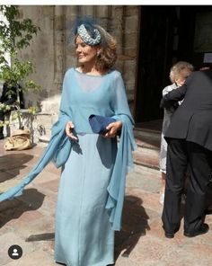 a woman in a blue dress is walking down the street