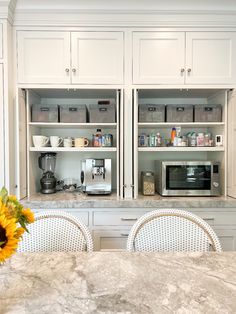 a kitchen with white cabinets and marble counter tops