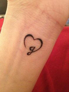 a small tattoo on the wrist of a person with a heart and an o - ring