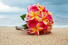 a bridal bouquet sitting on the sand at the beach