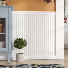 a blue cabinet sitting on top of a wooden floor next to a potted plant