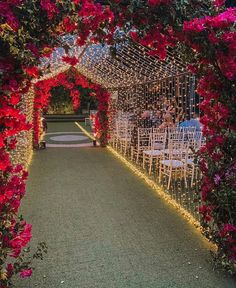 an outdoor wedding venue with red flowers on the aisle and white chairs in the middle