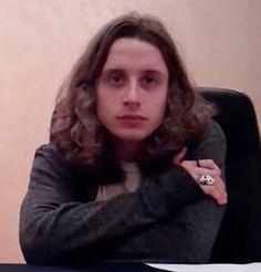 a woman sitting at a desk with her arms crossed and looking off to the side