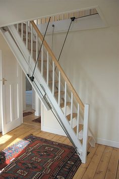 a stair case in an empty room with wood flooring and rug on the ground