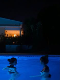 two children are playing in the pool at night