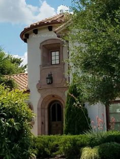 a tall white building with a clock on it's face and bushes around it