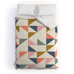 a bed covered in a white comforter with colorful geometric designs on the cover and pillow