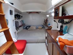 the interior of a small boat with a bed, desk and shelves on each side