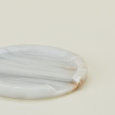 a white marble plate with an oval design on the edge and one piece of wood sticking out of it