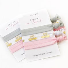 three different colored hair ties with gold and silver designs on them, one for swan and the other for sweet