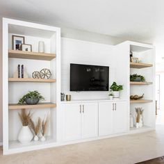 a living room with white walls and open shelvings on the wall, including a flat screen tv