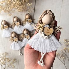 a hand holding a tiny angel ornament in front of small ones with flowers