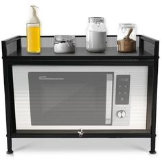 a microwave oven sitting on top of a black stand next to bottles and other items