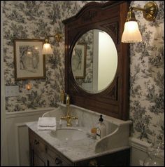 a bathroom with a sink, mirror and wallpapered walls in the background at night