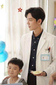 a man in a white lab coat standing next to a young boy