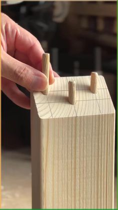 a person is placing wooden pegs on top of a piece of wood