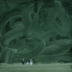 three people are standing in front of a green painting that looks like an abstract pattern