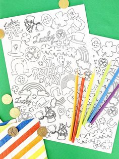 two coloring pages with colored pencils next to them on a green surface and gold coins