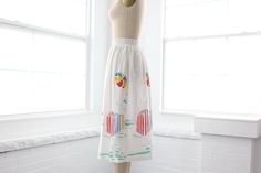 A quaint little 1970s vintage beach themed skirt with smocked elastic wast band. It is sheer so you’ll need a slip, or its perfect for pulling on after a swim. How cute would this be paired with a white, red, yellow, blue, or green bikini? Measurements of garment, allow space for fit.Taken flat, doubled for circumference.Shown on size 4 dress form.Length: 28.5”Waist: 22” to 36”Hips: 46”Swing: 56”Tag: SloganFabric: Polyester, RayonCondition: Excellent vintage. Tiny rust spot shown in photos. Summer Vacation Skirt With Elastic Waistband, Summer Cotton Skirt For Beach Season, Retro White Skirt For Summer, Retro Beach Skirt With Lining, Playful Beach Skirt For Summer, Summer Beach Gathered Skirt Bottoms, Summer Beach Bottoms With Gathered Skirt, Summer Beach Skirt With Elastic Waistband, White Lined Bottoms For Summer