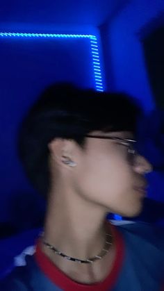 a blurry photo of a man with ear piercings on his ears in a blue room