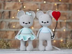 two crocheted teddy bears holding hands with a red heart in the other hand