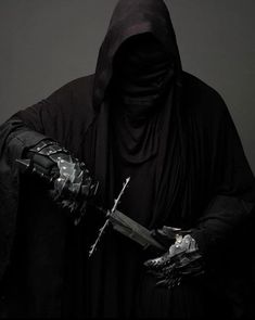 a man dressed in black holding a large knife and wearing a hood with his face covered