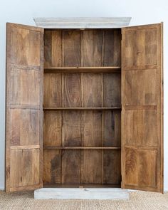 an open wooden bookcase sitting on top of a carpeted floor next to a wall