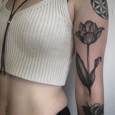 a woman's arm with tattoos on it and a flower tattoo on the side