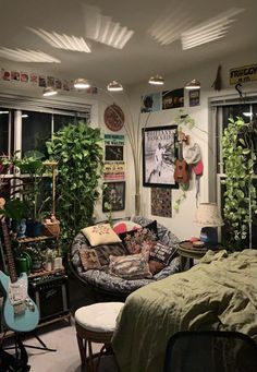 a room filled with lots of plants next to a bed and guitar hanging on the wall