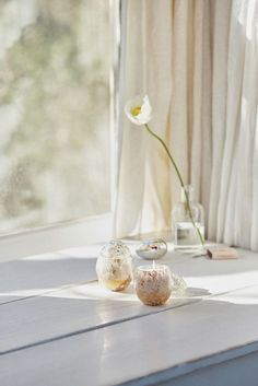 two vases with flowers in them sitting on a window sill