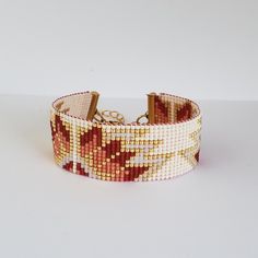 a close up of a bracelet on a white surface with red and gold beads,