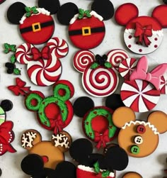 mickey and minnie mouse cookies are arranged on a white surface with candy canes in the shape of santa's helpers