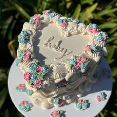 a heart shaped cake sitting on top of a white plate in front of some plants