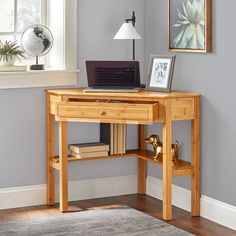 a laptop computer sitting on top of a wooden desk next to a lamp and books